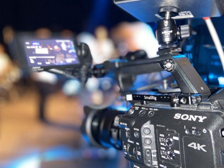 Kamera Sony na statywie przed sceną, w tle nieostre światła wydarzenia